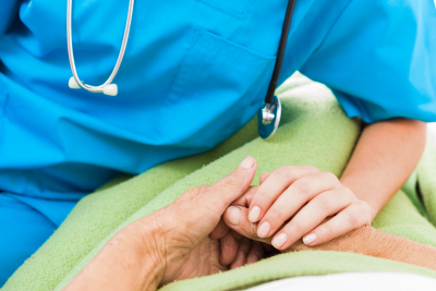 social services nurse holding elderly woman's hand with care